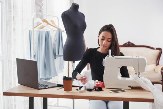 Does some calculations. Female fashion designer works on the new clothes in the workshop.