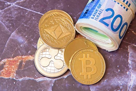 Horizontal view of cryptocurrency tokens, including Bitcoin, Ethererum Ripple, and Litecoin saw from above on Israeli Shekel ILS background. . High quality photo