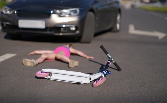 Girl lies on pavement after collision with cars on scooter. Accident with child pedestrian concept