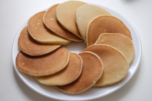 Flour sweet round fritters on white plate. Cooking pancakes concept