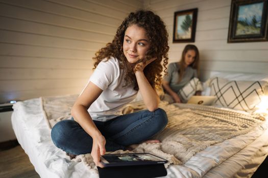 Two beautiful women lying in bed, holding and watching laptop