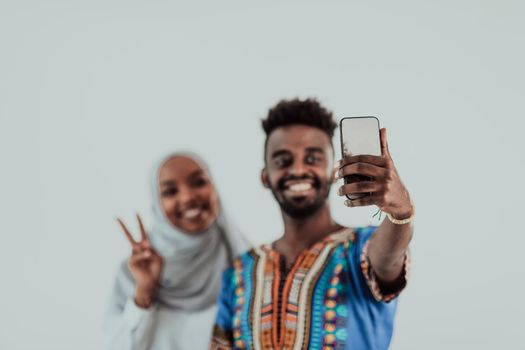 A young African couple taking a selfie on their smartphone, my shoes in traditional Sudan clothes. Selective focus. High-quality photo