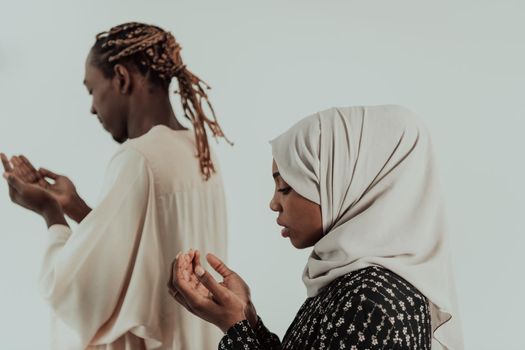 Handsome Young African Muslim Man And Muslim Hijab Woman Making Traditional Fatiha Prayer To Allah God While Wearing A Traditional Sudan fashion clothes in studio. High-quality photo
