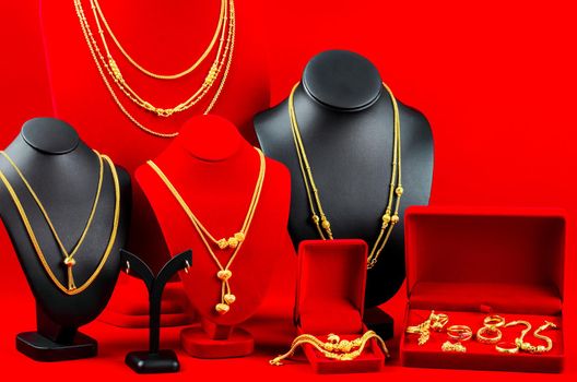 Accessory and gold jewelry necklace display stand with gold necklace on red Velvet fabric.
