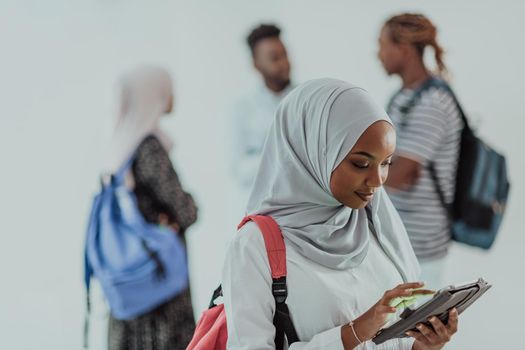 African female student with a group of friends in the background wearing traditional Islamic hijab clothes. Selective focus. High-quality photo