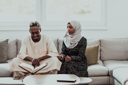 African Muslim couple at home in Ramadan reading Quran holly Islam book. High-quality photo