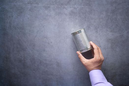 man holding a canned food on black background .