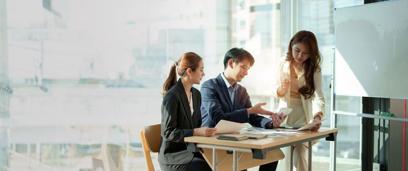 Group of business asian people working on graph chart, talking, planning analyze investment and marketing on tablet in office.