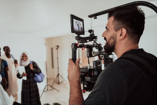 A videographer in a home studio captures a group of modern students with a professional camera. High-quality photo