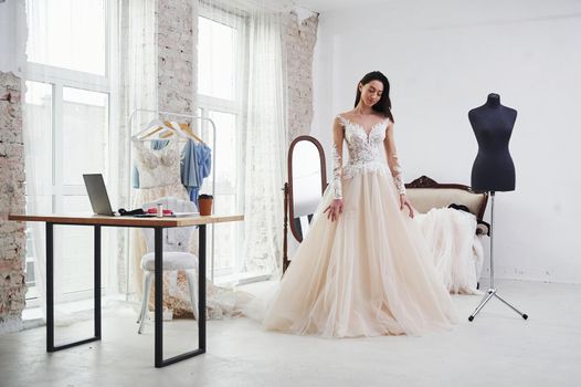 Portrait on the white clean room. The process of fitting the dress in the studio of hand crafted clothes.