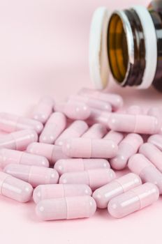 The Pink capsule pills with bottle on pink background