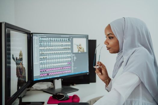 Young Afro-American modern Muslim businesswoman wearing a scarf in a creative bright office workplace with a big screen. High-quality photo