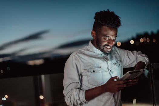 The young man on an urban city street at night texting on a smartphone with bokeh and neon city lights in the background. High-quality photo. High-quality photo