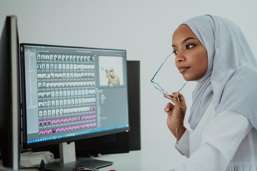 Young Afro-American modern Muslim businesswoman wearing a scarf in a creative bright office workplace with a big screen. High-quality photo