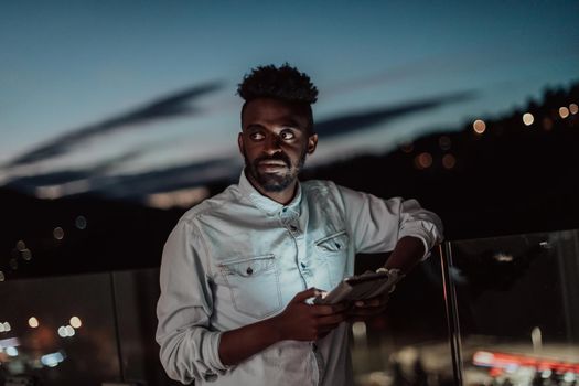 The young man on an urban city street at night texting on a smartphone with bokeh and neon city lights in the background. High-quality photo. High-quality photo