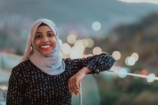 Young Muslim woman wearing scarf veil on urban city street at night texting on a smartphone with bokeh city light in the background. High-quality photo