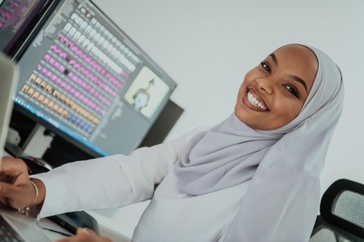 Young Afro-American modern Muslim businesswoman wearing a scarf in a creative bright office workplace with a big screen. High-quality photo