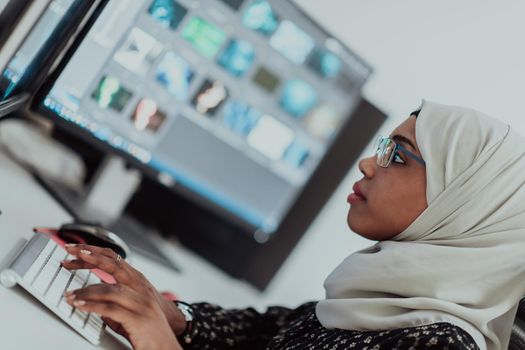 Young Afro-American modern Muslim businesswoman wearing a scarf in a creative bright office workplace with a big screen. High-quality photo