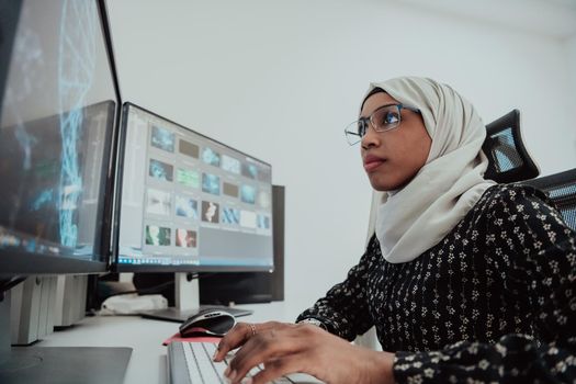 Young Afro-American modern Muslim businesswoman wearing a scarf in a creative bright office workplace with a big screen. High-quality photo