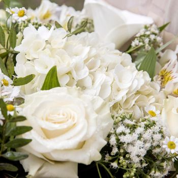 Wedding bouquet of white flowers are roses, hydrangeas, chamomile, wrapped in craft paper