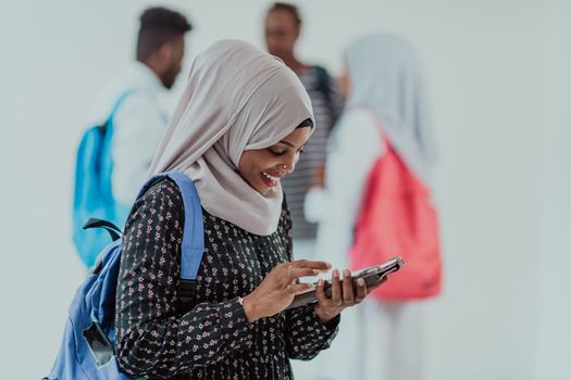 African female student with a group of friends in the background wearing traditional Islamic hijab clothes. Selective focus. High-quality photo