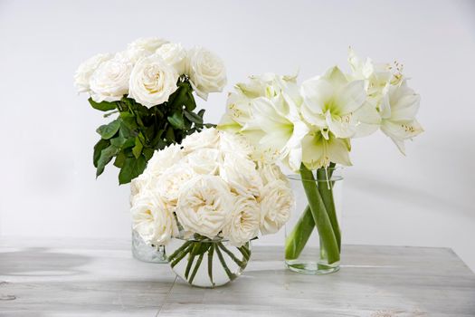 White roses, lily in round vases on the table for a special occasion as a kitchen decoration. Copy space