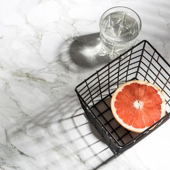 Summer stationery still life scene. CloseUp of cut grapefruit fruit on white table background in sunlight. Blank paper cards, invitations mockup scene, long palms branches shadows. Flat lay, top view.