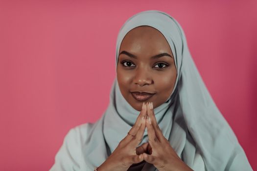 Portrait of young modern muslim afro beauty wearing traditional islamic clothes on plastic pink background. Selective focus. High quality photo