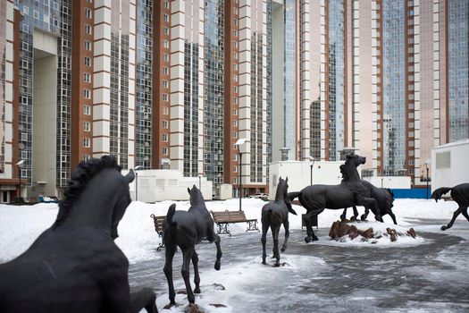 Moscow, Russia - 31 January 2021, A playground in the courtyard of a multi-storey residential building in Khimki, Moscow region. sculpture Horses running in a circle on the playground