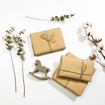 Dry eucalyptus branches and gifts wrapped in craft paper. Empty space. Copy space. Top view