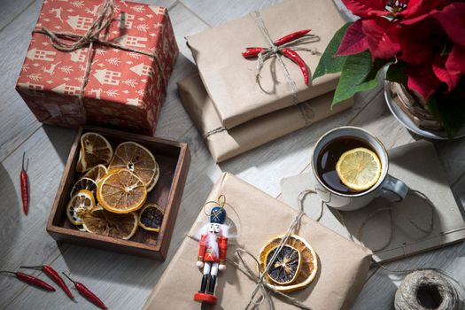 Dry orange circles in a wooden box made of mango wood, wrapped in craft paper and tied with twine, gifts, a mug with tea with lemon. Preparing for Christmas. Copy space