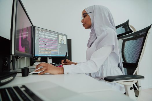 Young Afro-American modern Muslim businesswoman wearing a scarf in a creative bright office workplace with a big screen. High-quality photo