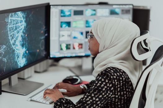 Young Afro-American modern Muslim businesswoman wearing a scarf in a creative bright office workplace with a big screen. High-quality photo