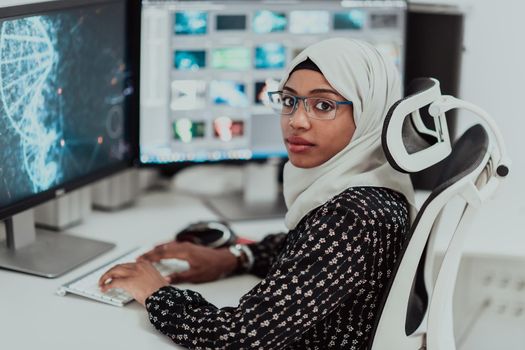 Young Afro-American modern Muslim businesswoman wearing a scarf in a creative bright office workplace with a big screen. High-quality photo