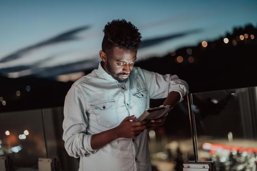 The young man on an urban city street at night texting on a smartphone with bokeh and neon city lights in the background. High-quality photo. High-quality photo