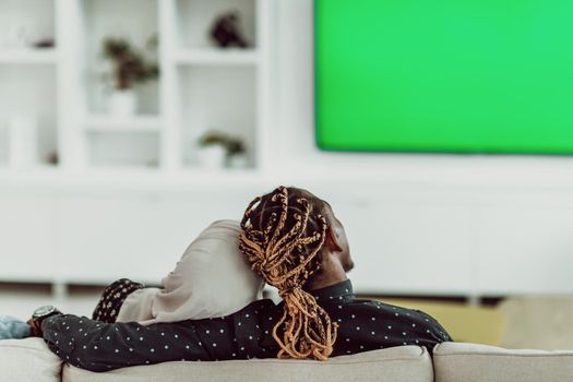 African Couple Sitting On Sofa Watching TV Together Chroma Green Screen Woman Wearing Islamic Hijab Clothes. High quality photo