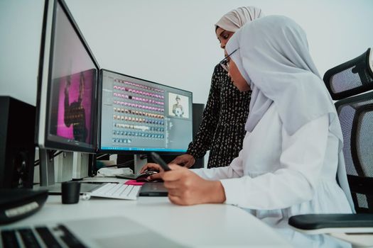 Friends at the office are two young Afro-American modern Muslim businesswomen wearing scarfs in a creative bright office workplace with a big screen. High-quality photo