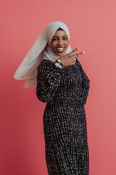 Portrait of young modern muslim afro beauty wearing traditional islamic clothes on plastic pink background. Selective focus. High quality photo