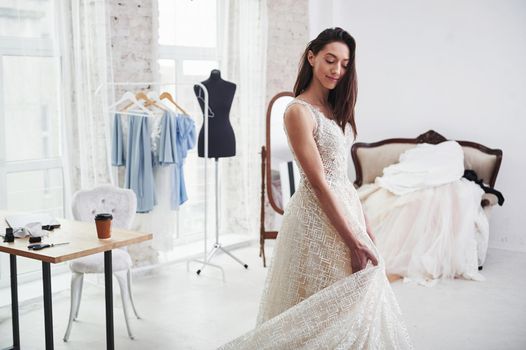 Touching lower part of brand new wear. The process of fitting the dress in the studio of hand crafted clothes.