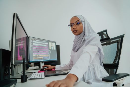 Young Afro-American modern Muslim businesswoman wearing a scarf in a creative bright office workplace with a big screen. High-quality photo