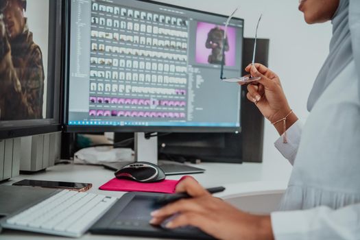 Young Afro-American modern Muslim businesswoman wearing a scarf in a creative bright office workplace with a big screen. High-quality photo