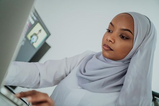 Young Afro-American modern Muslim businesswoman wearing a scarf in a creative bright office workplace with a big screen. High-quality photo