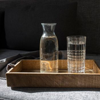 A refreshing glass of water, a bottle of water and on a tray, a linen napkin on the couch in the summer heat
