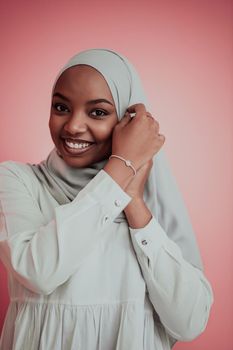 Portrait of young modern muslim afro beauty wearing traditional islamic clothes on plastic pink background. Selective focus. High quality photo