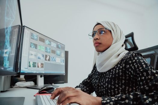 Young Afro-American modern Muslim businesswoman wearing a scarf in a creative bright office workplace with a big screen. High-quality photo