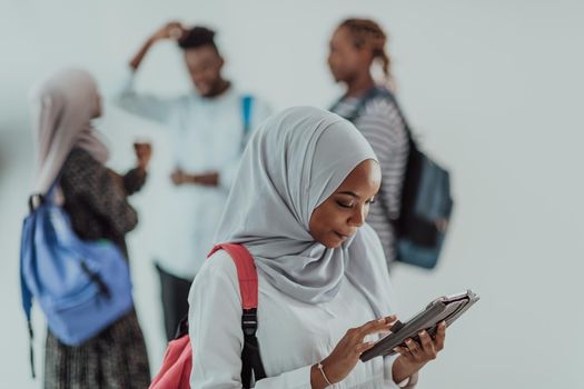 African female student with a group of friends in the background wearing traditional Islamic hijab clothes. Selective focus. High-quality photo