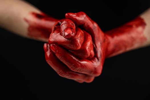 Women's fists in blood on a black background. Fist and palm
