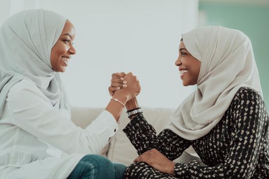 African women arm wrestling conflict concept, disagreement, and confrontation wearing traditional Islamic hijab clothes. Selective focus. High-quality photo