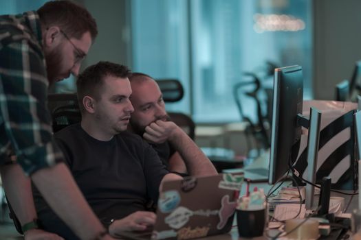 A photo of three men staring intently at a computer while sitting in a modern office. Selective focus. High-quality photo