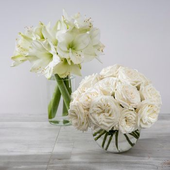 White roses, lily in round vases on the table for a special occasion as a kitchen decoration. Copy space. Square frame